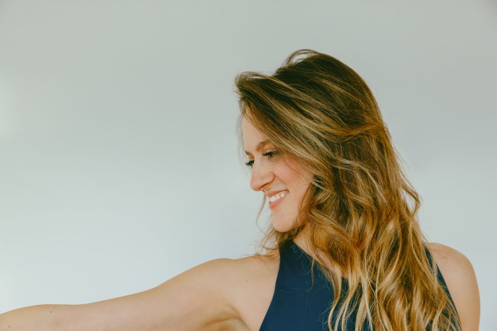 Giada smiling and looking down over her shoulder, one arm extended