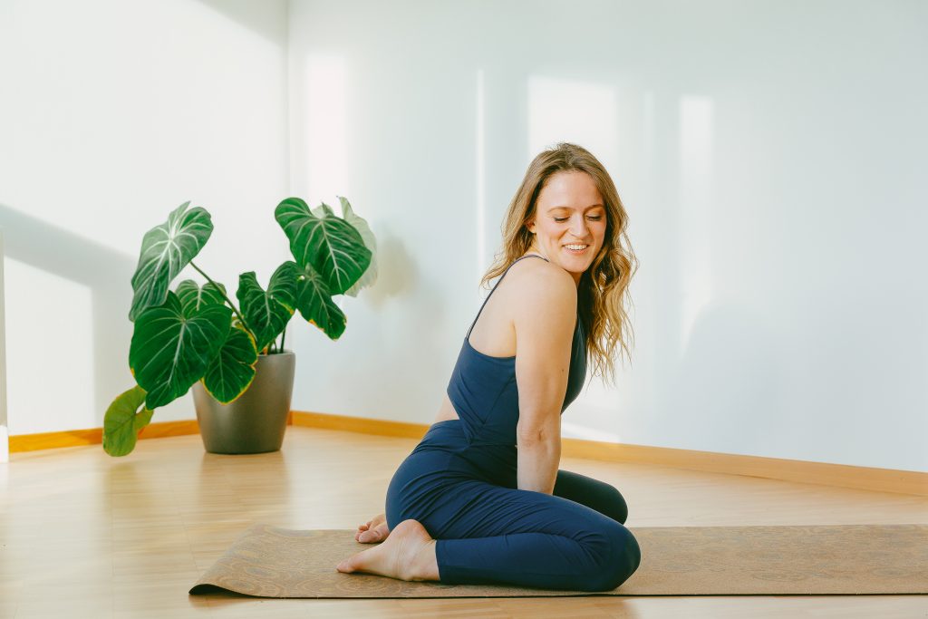 Giada kneeling on a yoga mat, smiling over her shoulder